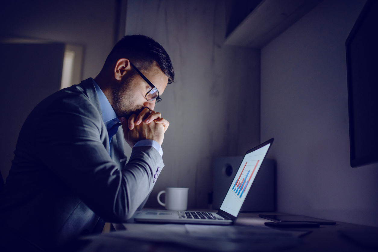 Homme d'affaires caucasien se penchant sur le bureau et regardant des diagrammes avec une expression sérieuse